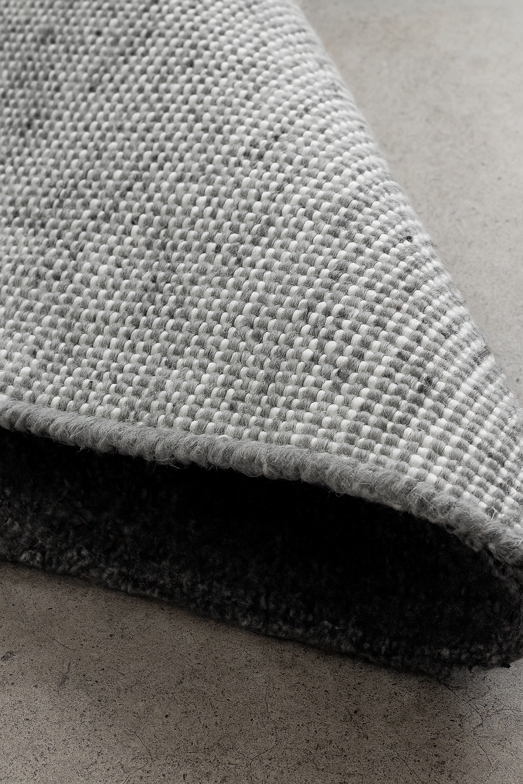 Close-up of a textured gray rug on a concrete floor laine 100% naturelle tapis fais a la main naturug hand made rug morocco maroc marocain